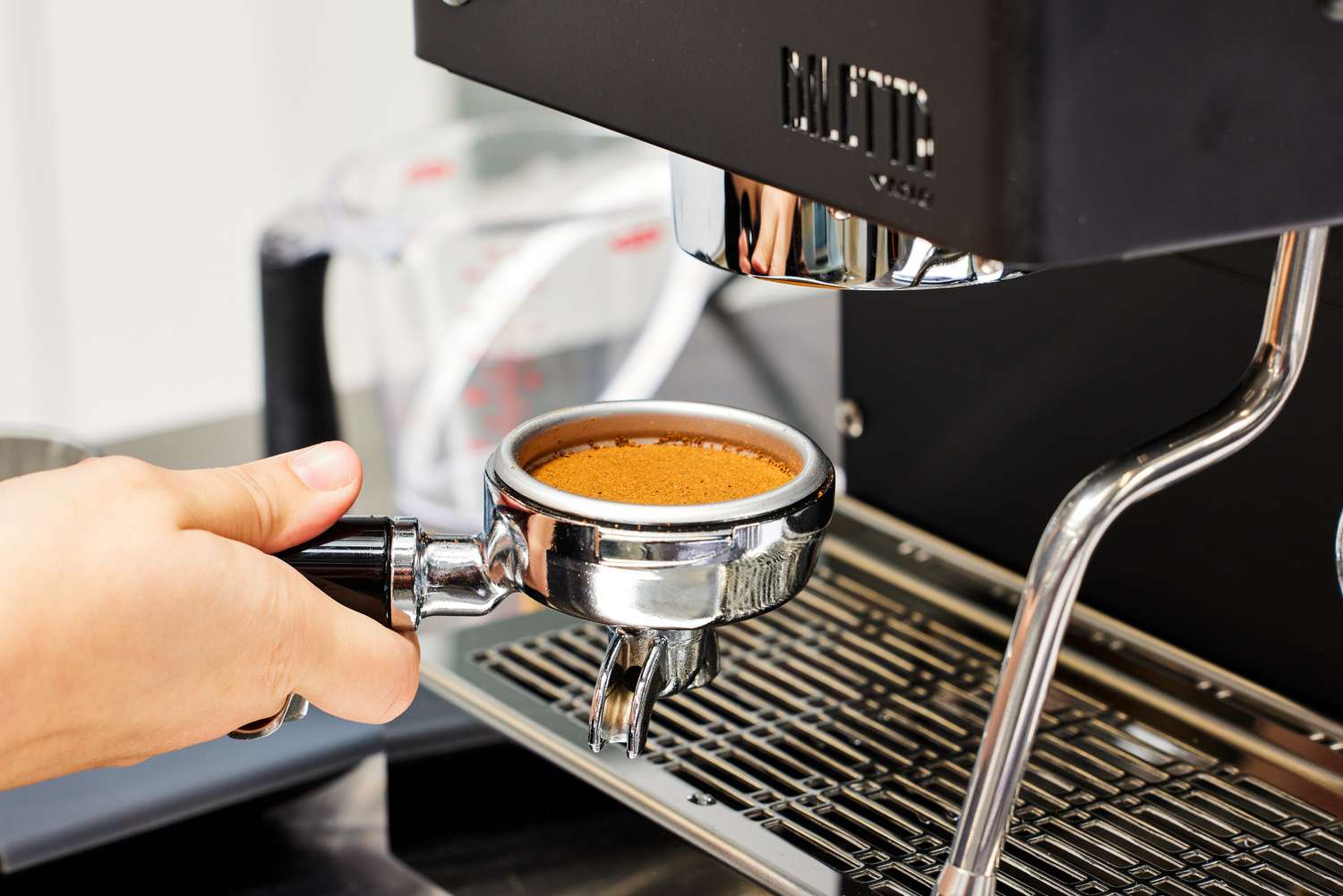 Hand holding the portafilter filled with coffee grounds next to the Diletta Mio Espresso Machine