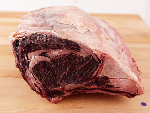 A prime rib roast that's been dry-aged at home on a wooden cutting board. 