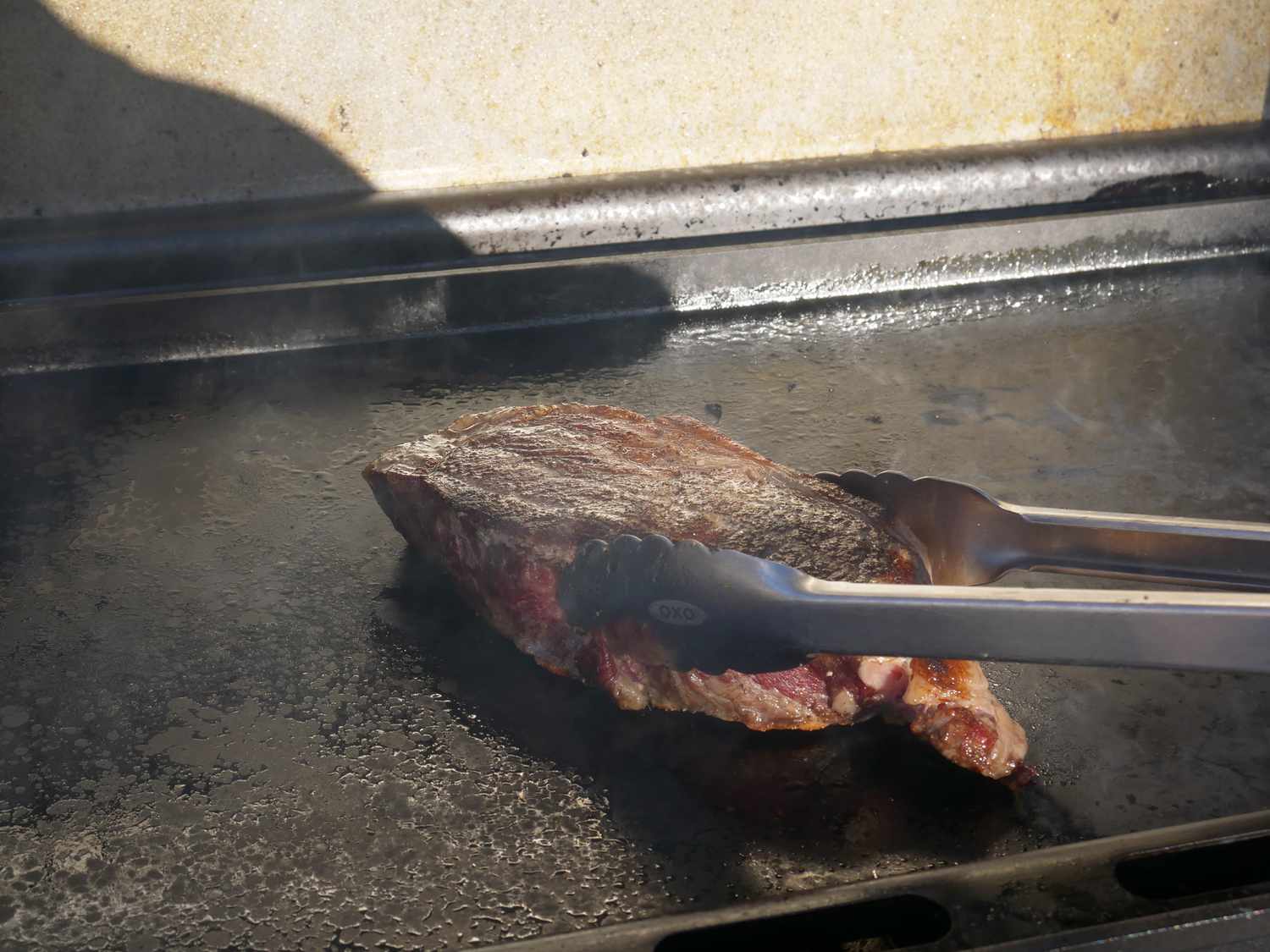 flipping a piece of steak on the griddle