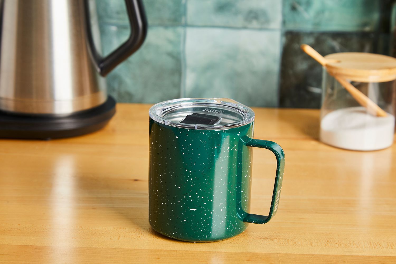 A green MiiR camp cup on a kitchen countertop.