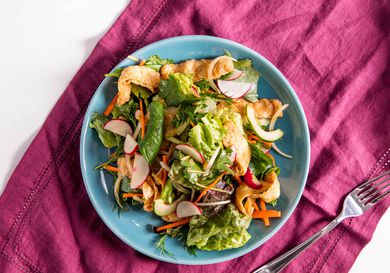 Overhead view of vegan tofu and herb salad, served on a light blue plate.