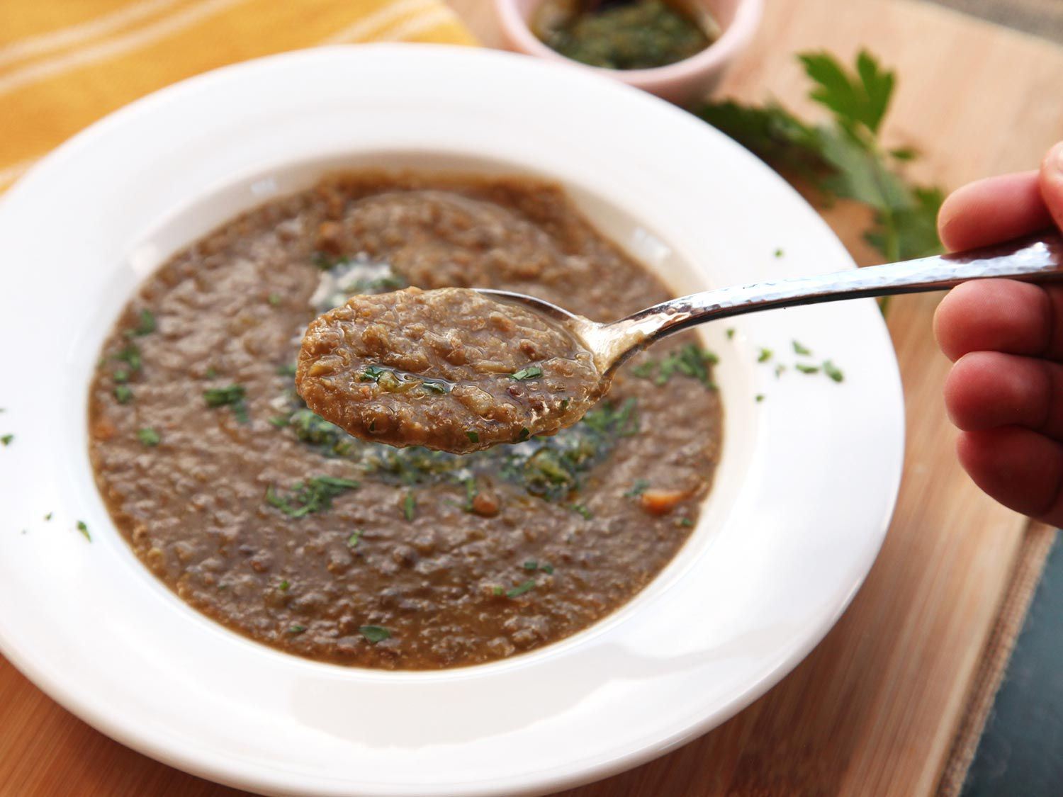 Taking a spoonful of lentil soup, garnished with gremolata.
