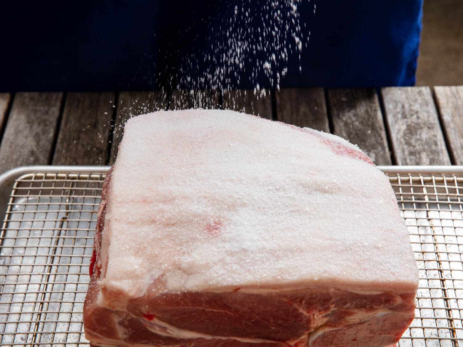 The pork shoulder is sprinkled with salt.