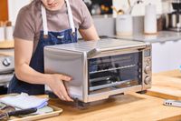 A person placing the Breville the Compact Smart Oven onto wood