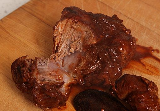 A chunk of pork cooked as carne adovada, torn in half to expose the meat fibers inside. 