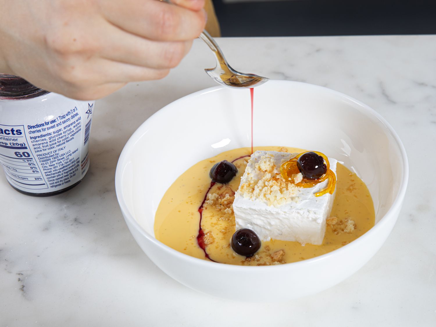 Ile flottante being drizzle with cherry syrup