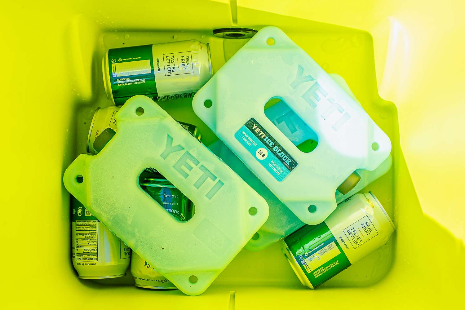 Yeti ice blocks and beverage cans inside a yellow cooler