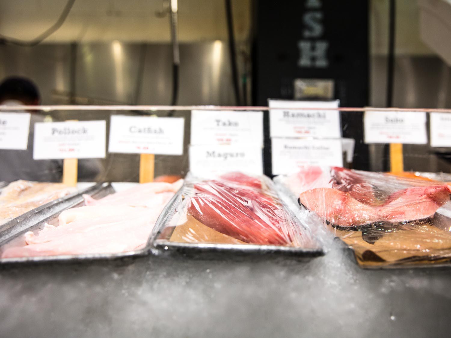 Fresh sushi-grade fish on display over ice at a market.