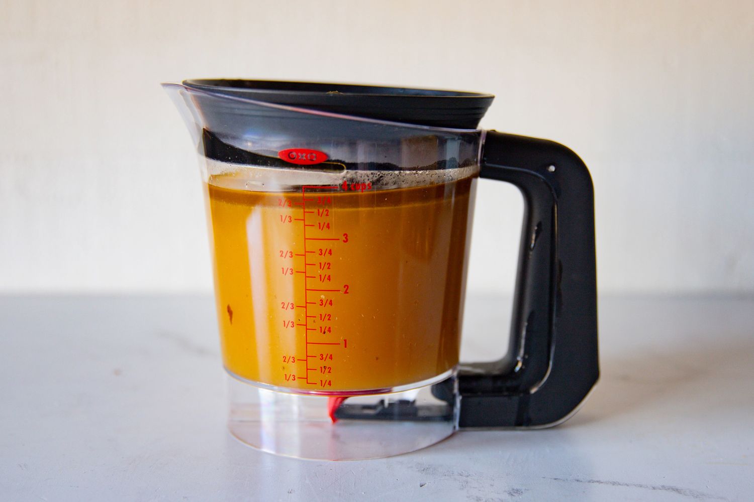 A measuring cup filled with liquid and a black handle markings in red indicating volume on the cup