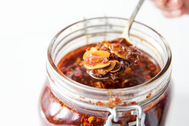 Homemade spicy chili crisp being spooned out of a jar.