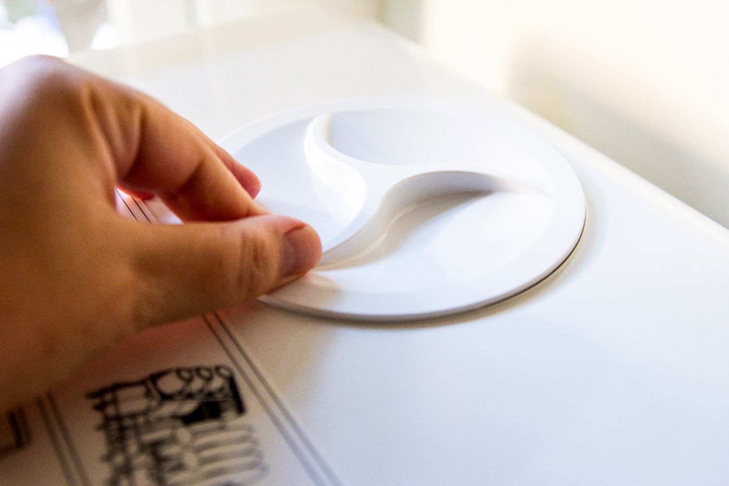 A person adjusting the water tank cover on a countertop dishwasher.