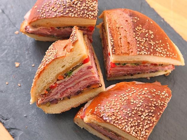 A quartered muffuletta sandwich on a slate board.