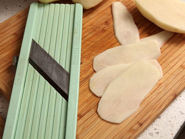 Peeled russet potato sliced on a mandoline.