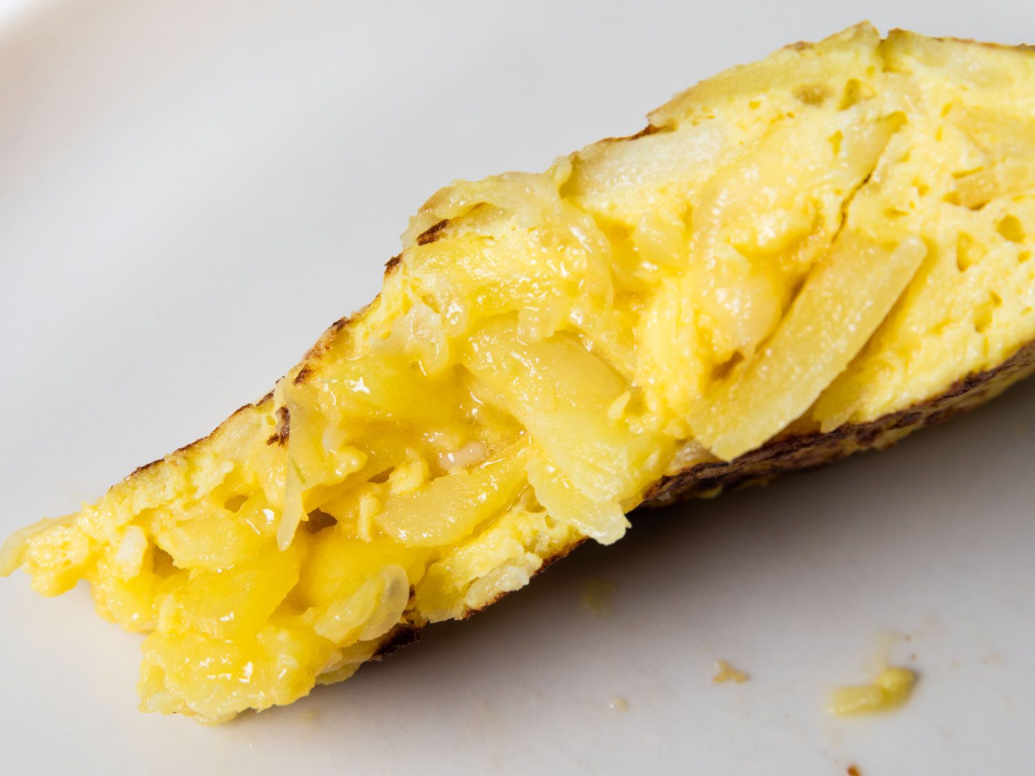 Slice of Spanish potato and onion tortilla showing a creamy, dense center.
