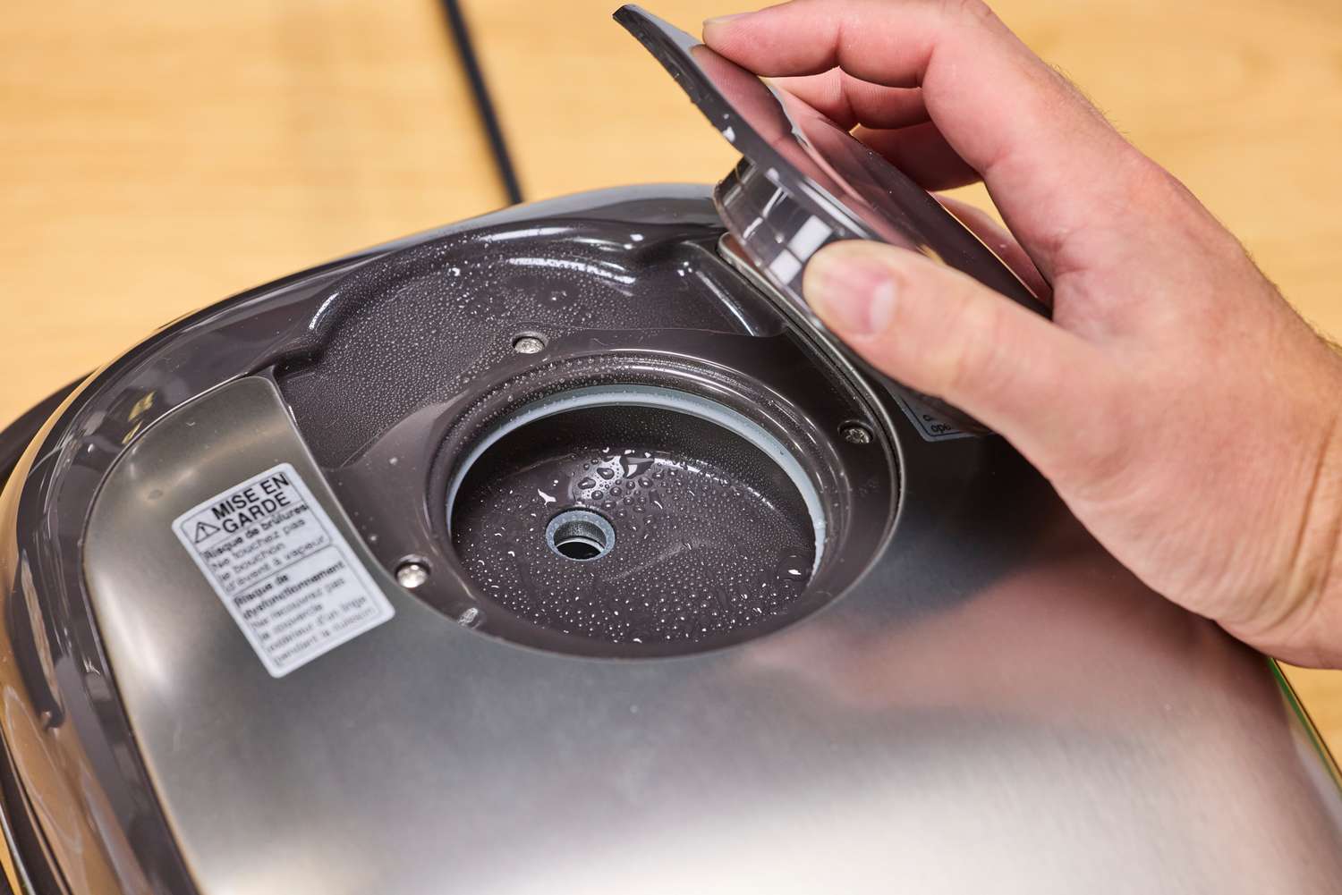 A person opens the steam cover on the Zojirushi NS-TSC10 Miacom Rice Cooker and Warmer