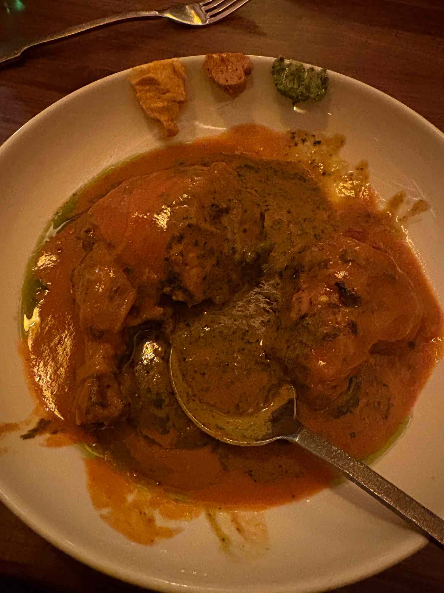 A dish with a rich sauce and pieces of bread on the side