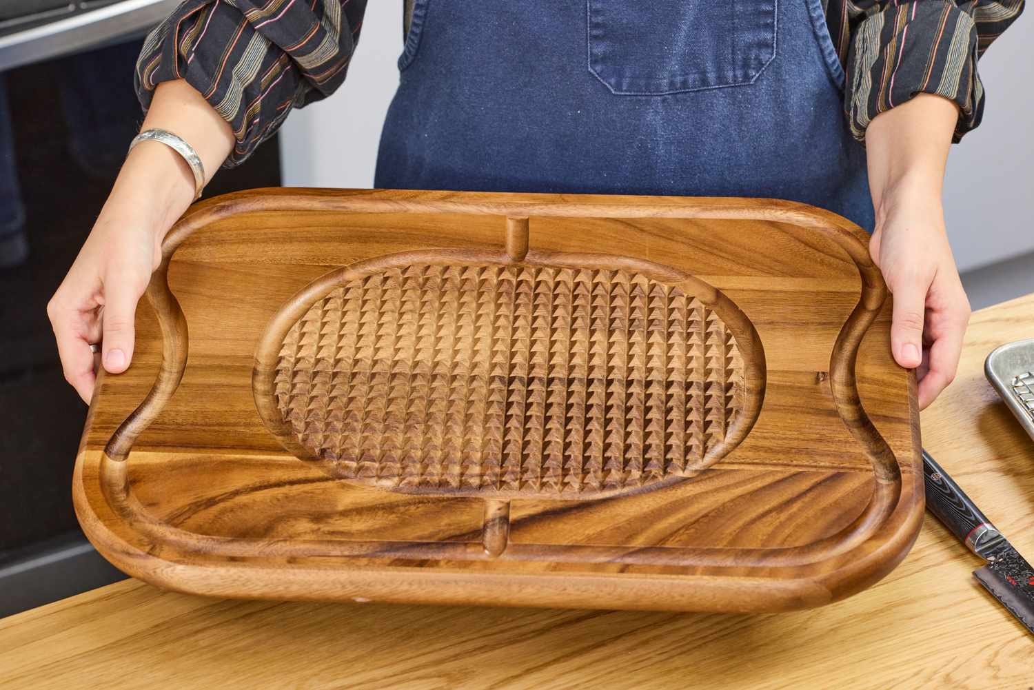 Person holding a Lipper International Acacia Cutting Board with Grid Grip