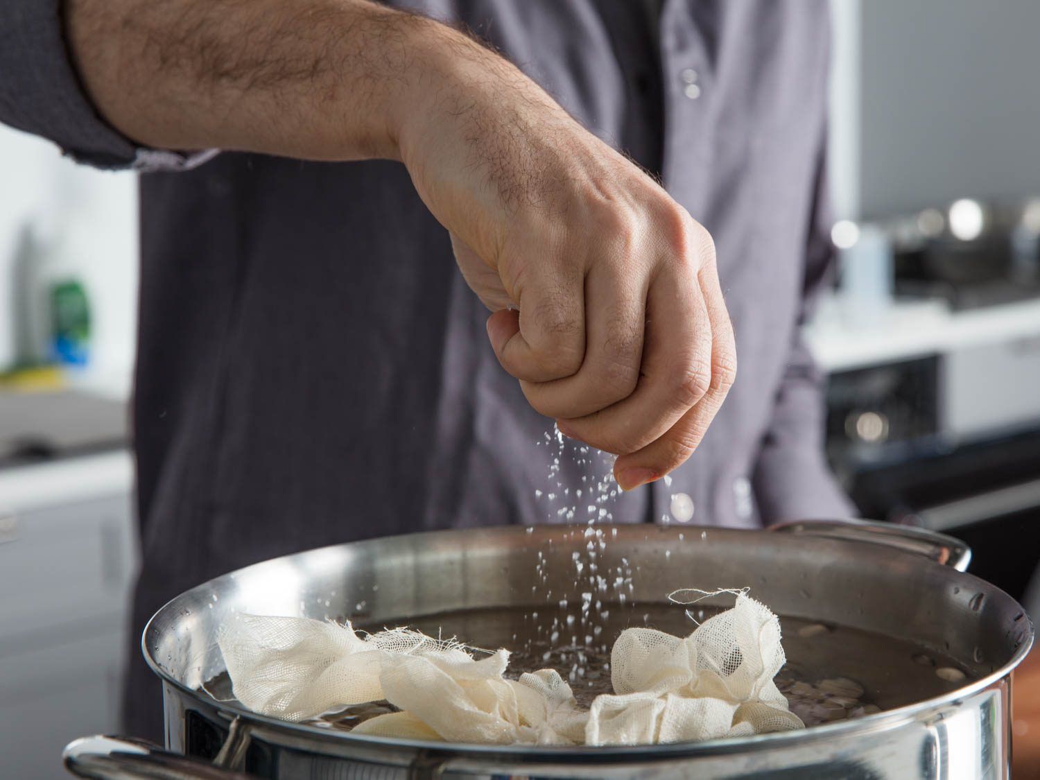 Sprinkling salt into a pot of water filled with dried beans and aromatics