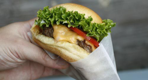 Author holding the assembled fakeshack burger, cradled in wax paper.