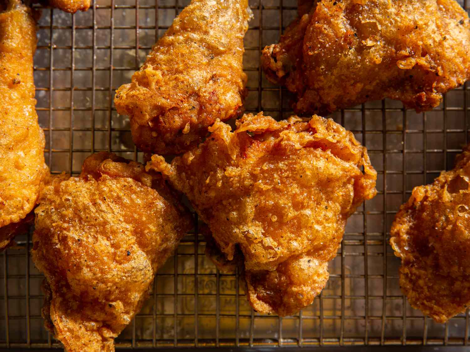 Batter-fried chicken pieces on wire rack set in rimmed baking sheet