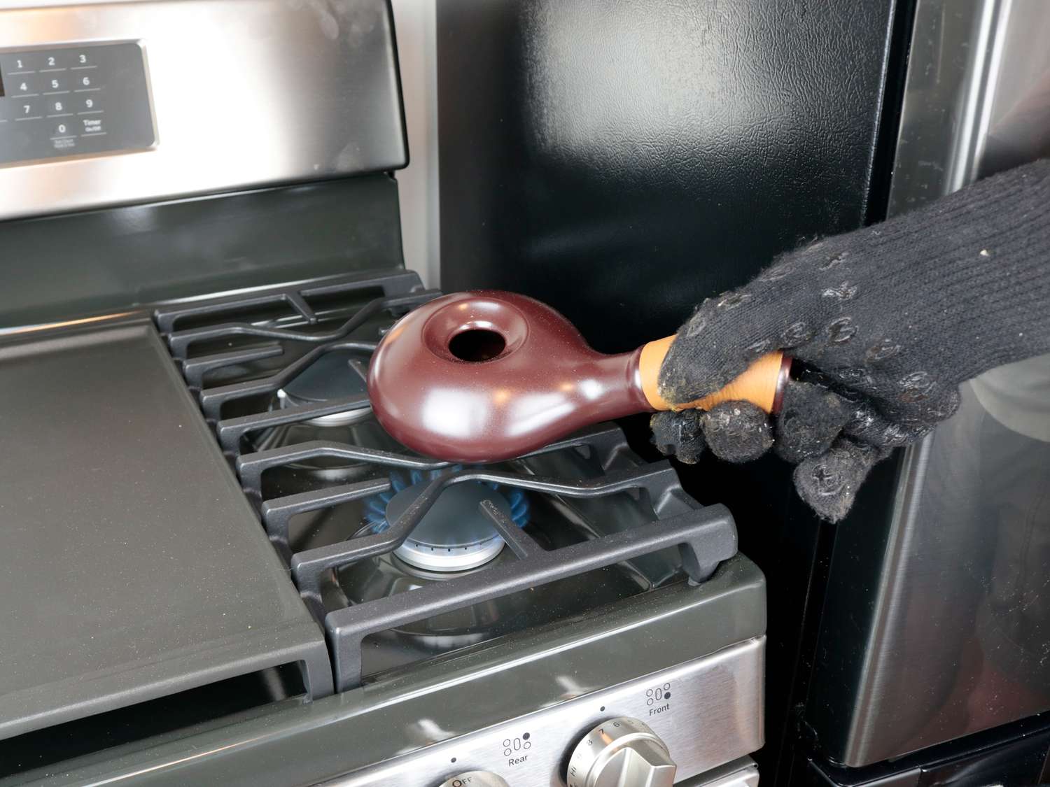 a handheld coffee roaster over an oven burner