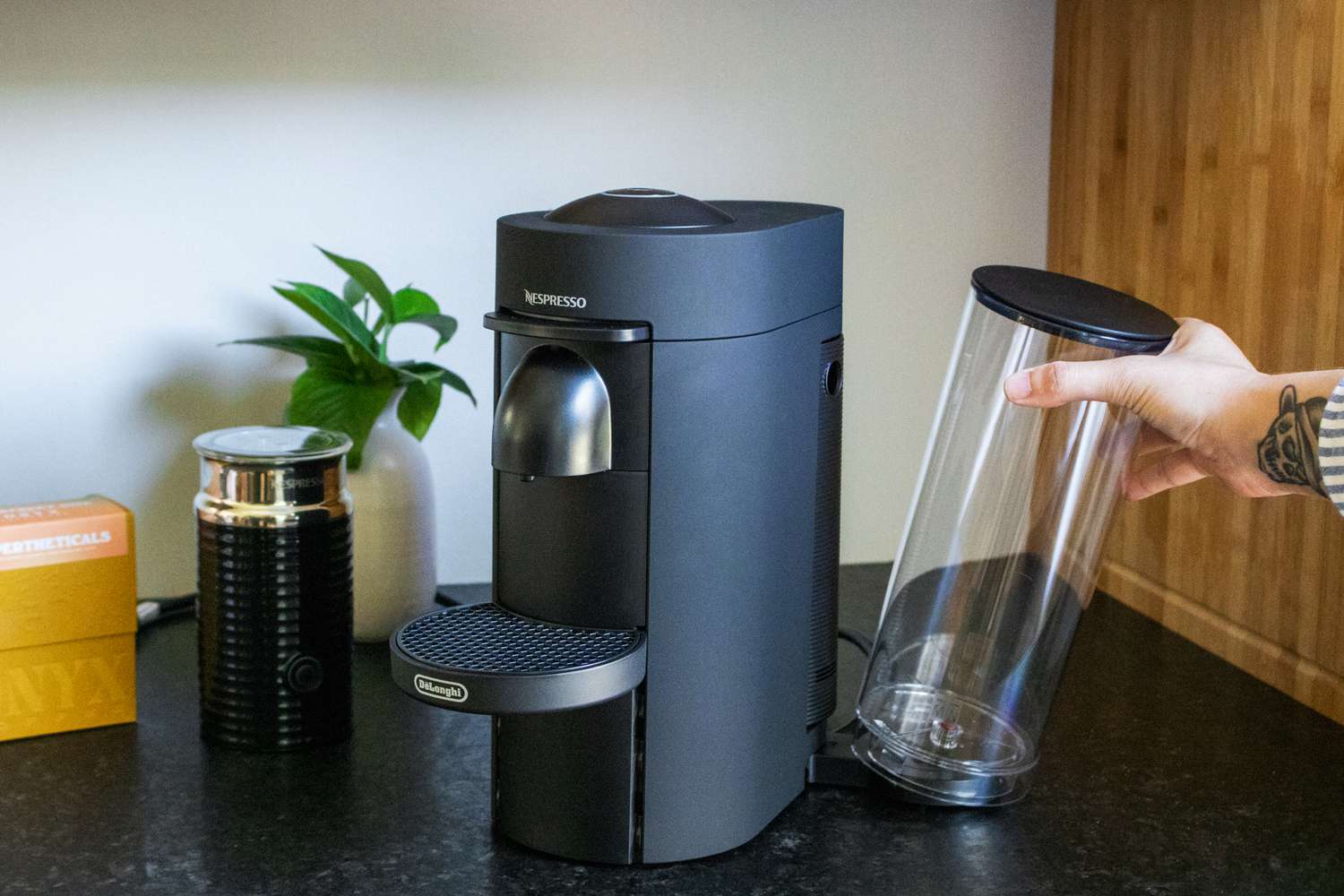 A hand removing the brew tank from a Nespresso machine