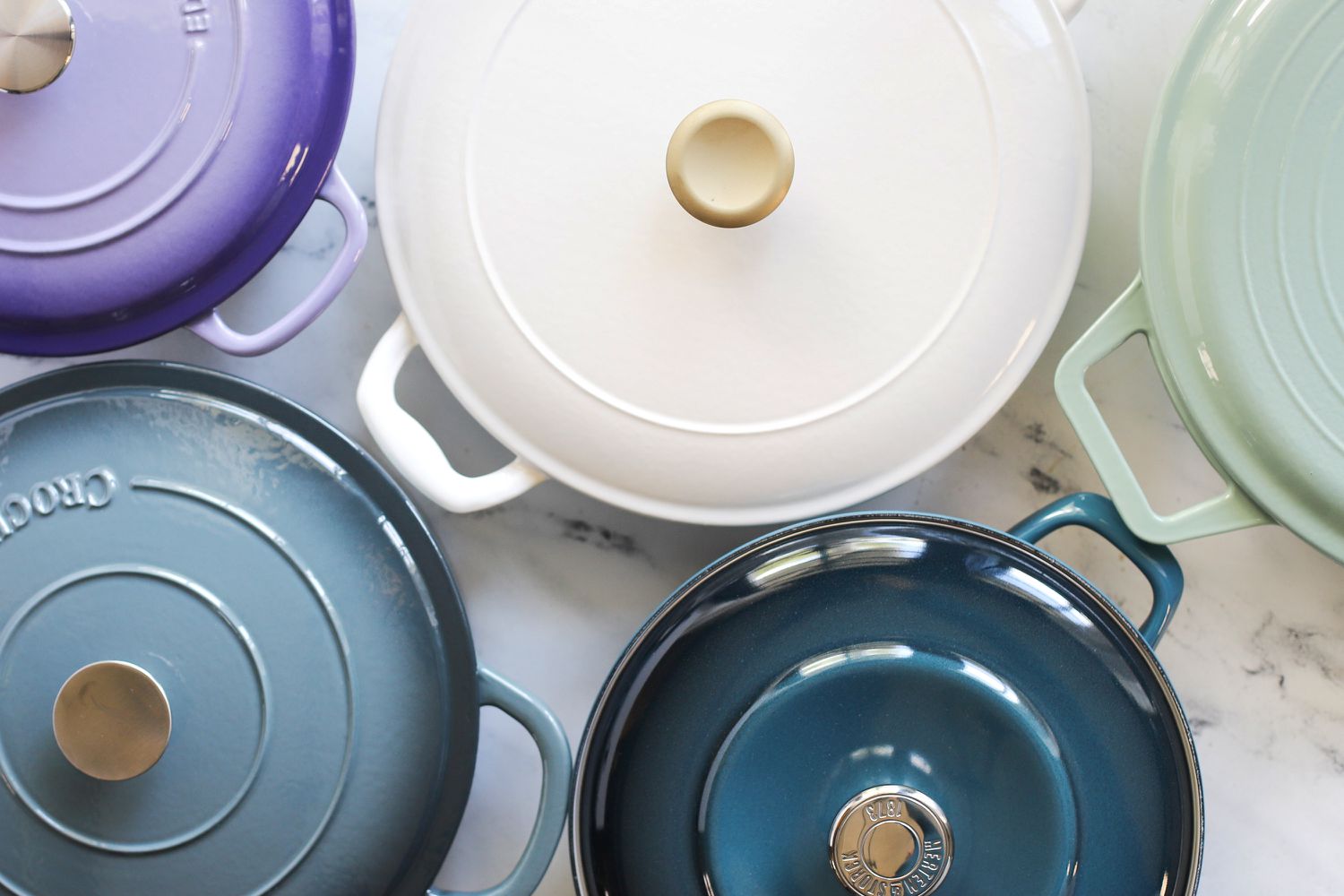 A group shot of enameled cast iron braisers sitting next to each other.