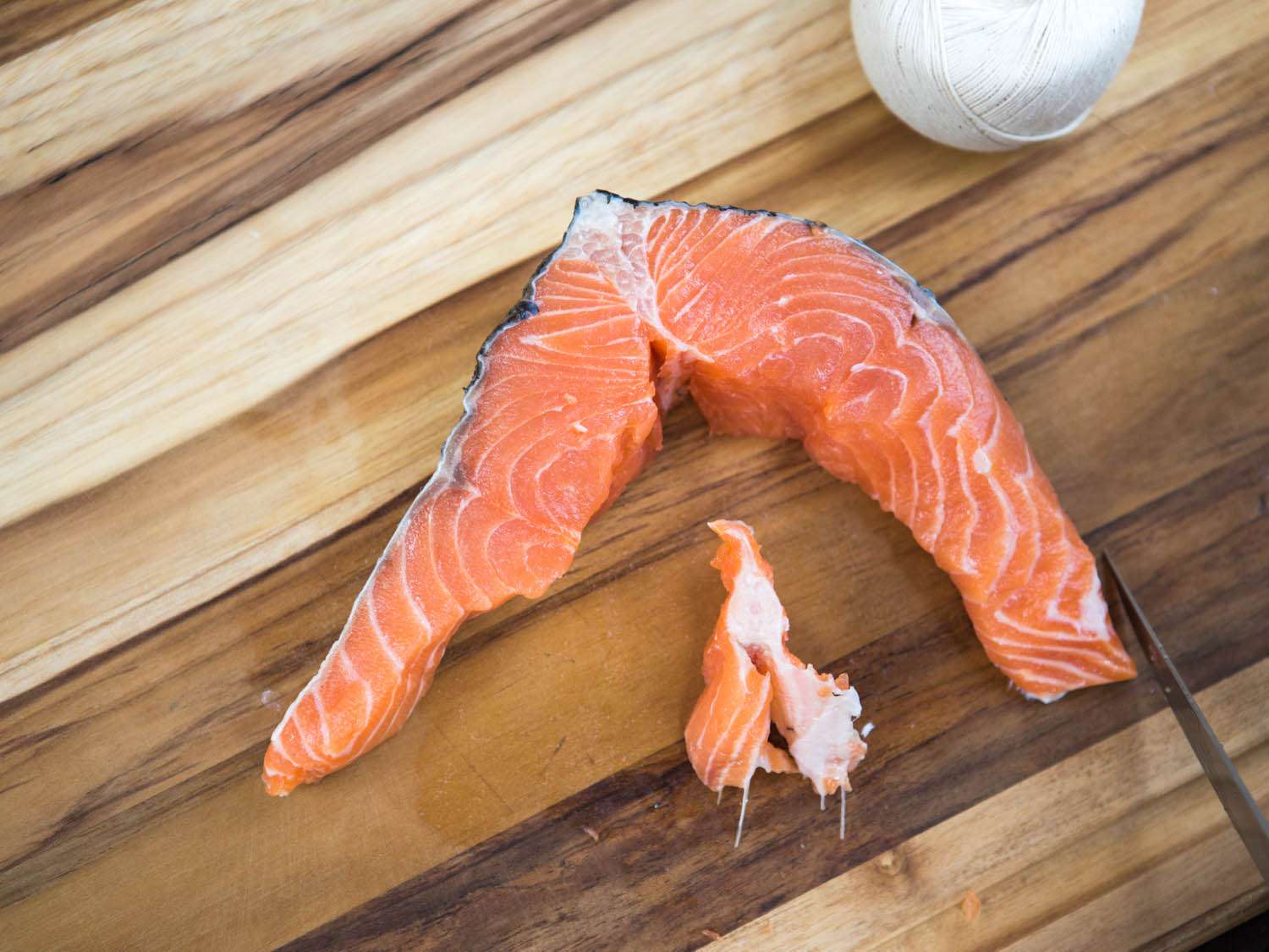 The spine bone is cut free from the center of a salmon steak.