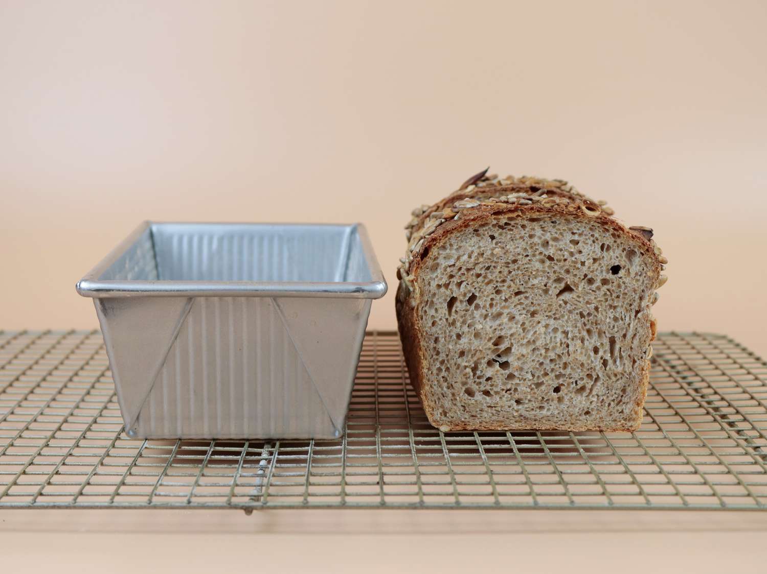 a loaf pan next to a tall wheat bread loaf
