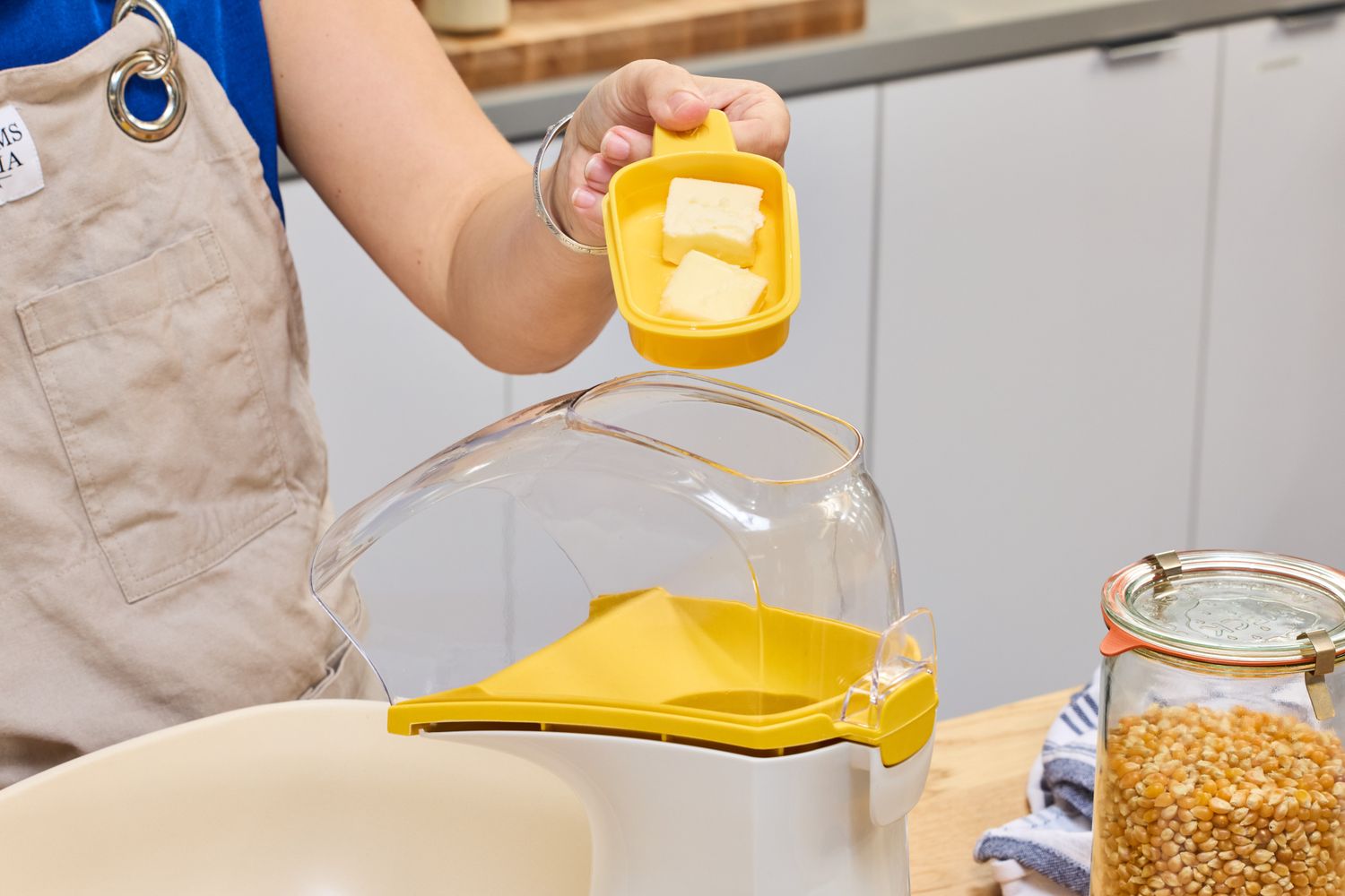 A person places a butter tray on top of the Presto Poplite Hot Air Popper