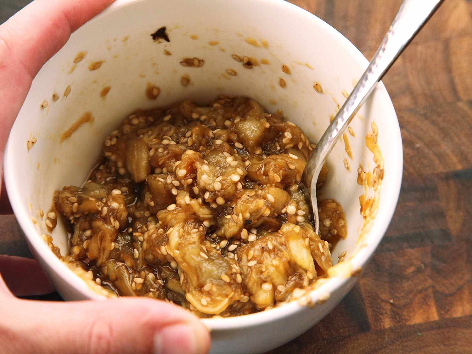 Roasted eggplant mixed with seasonings and sesame seeds in a small white bowl to use for a topping for creamy vegan ramen.