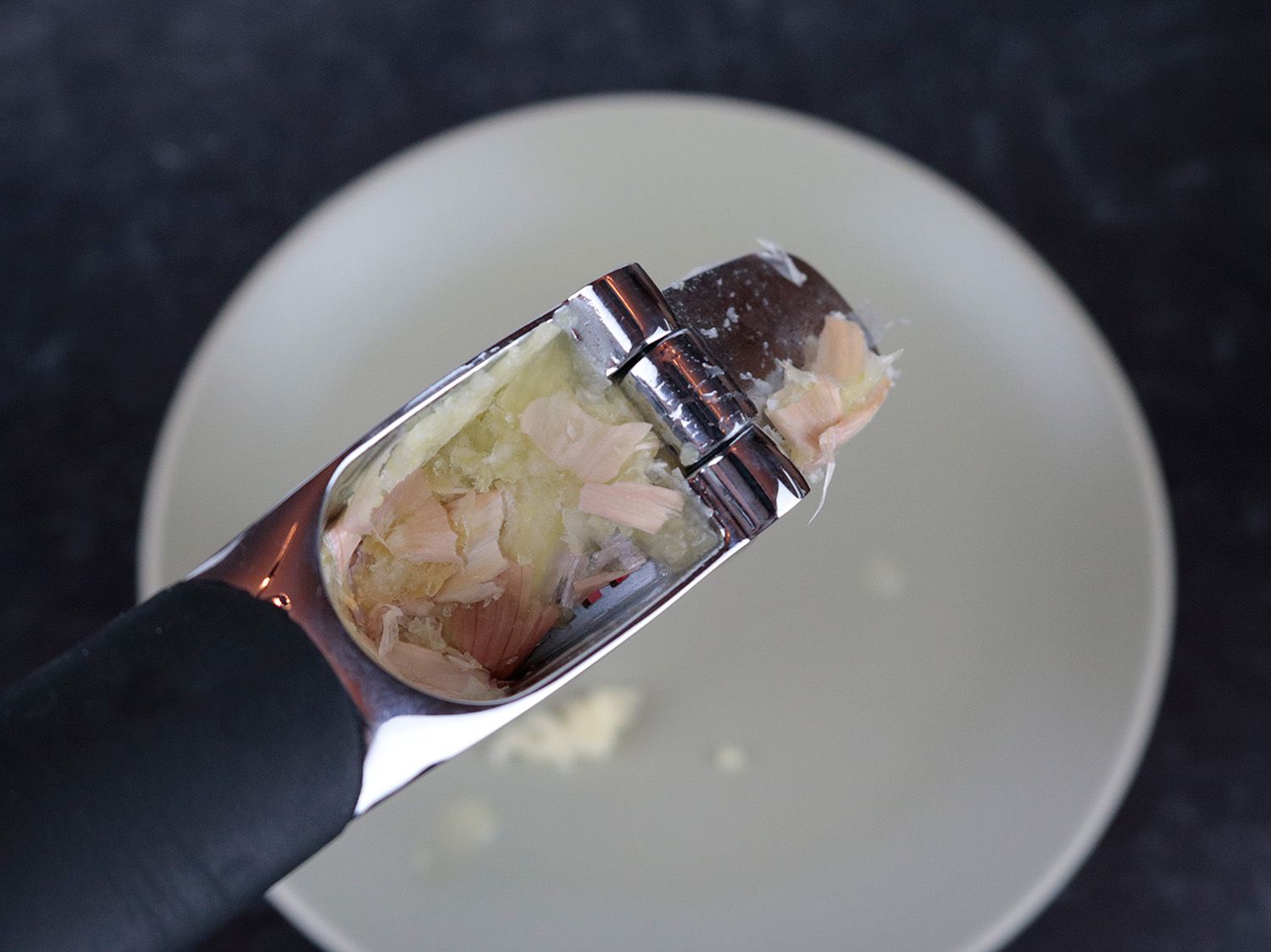the inside of a garlic press with mashed unpeeled cloves leaving lots of residue