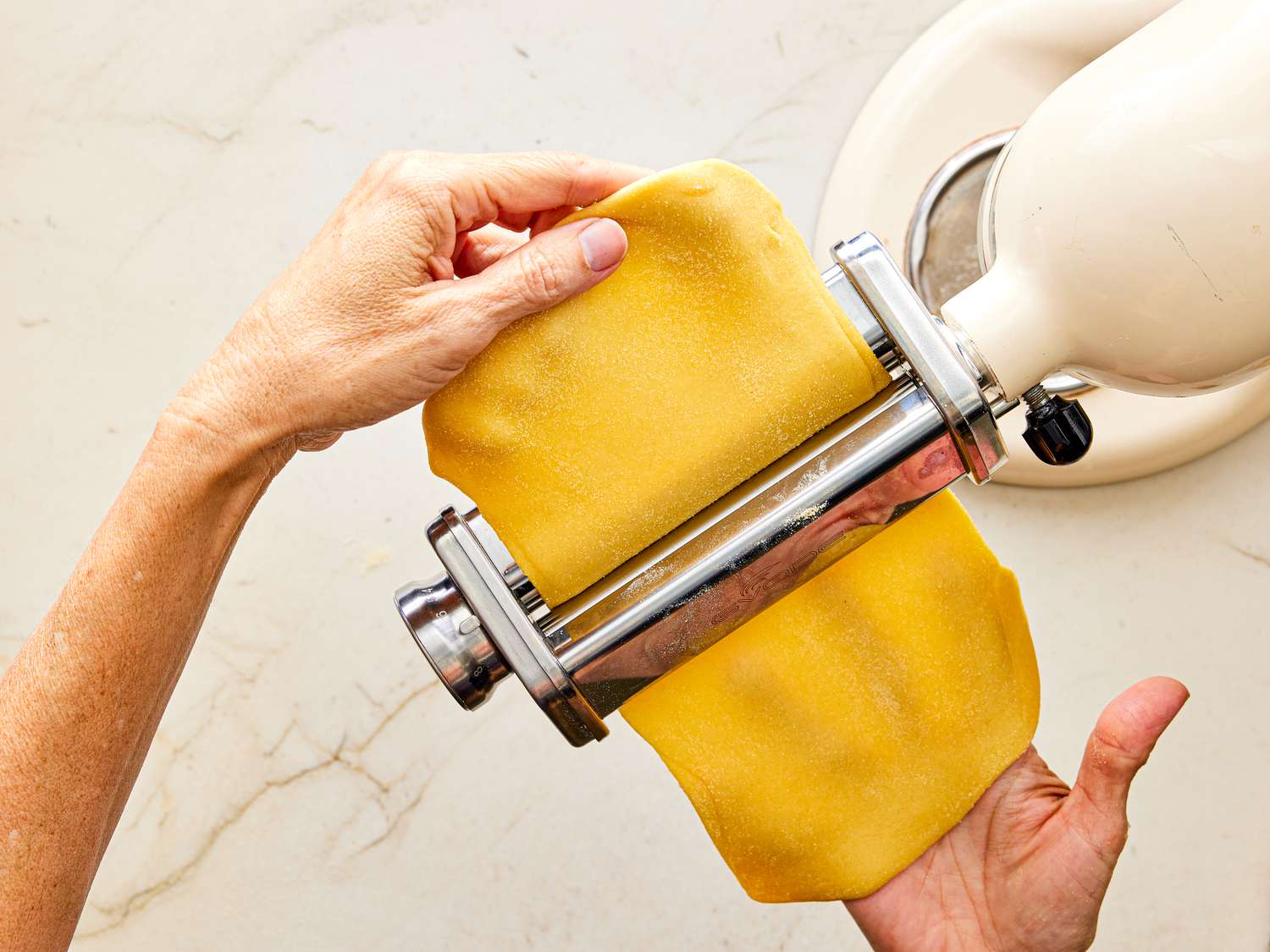 Running pasta through roller machine 