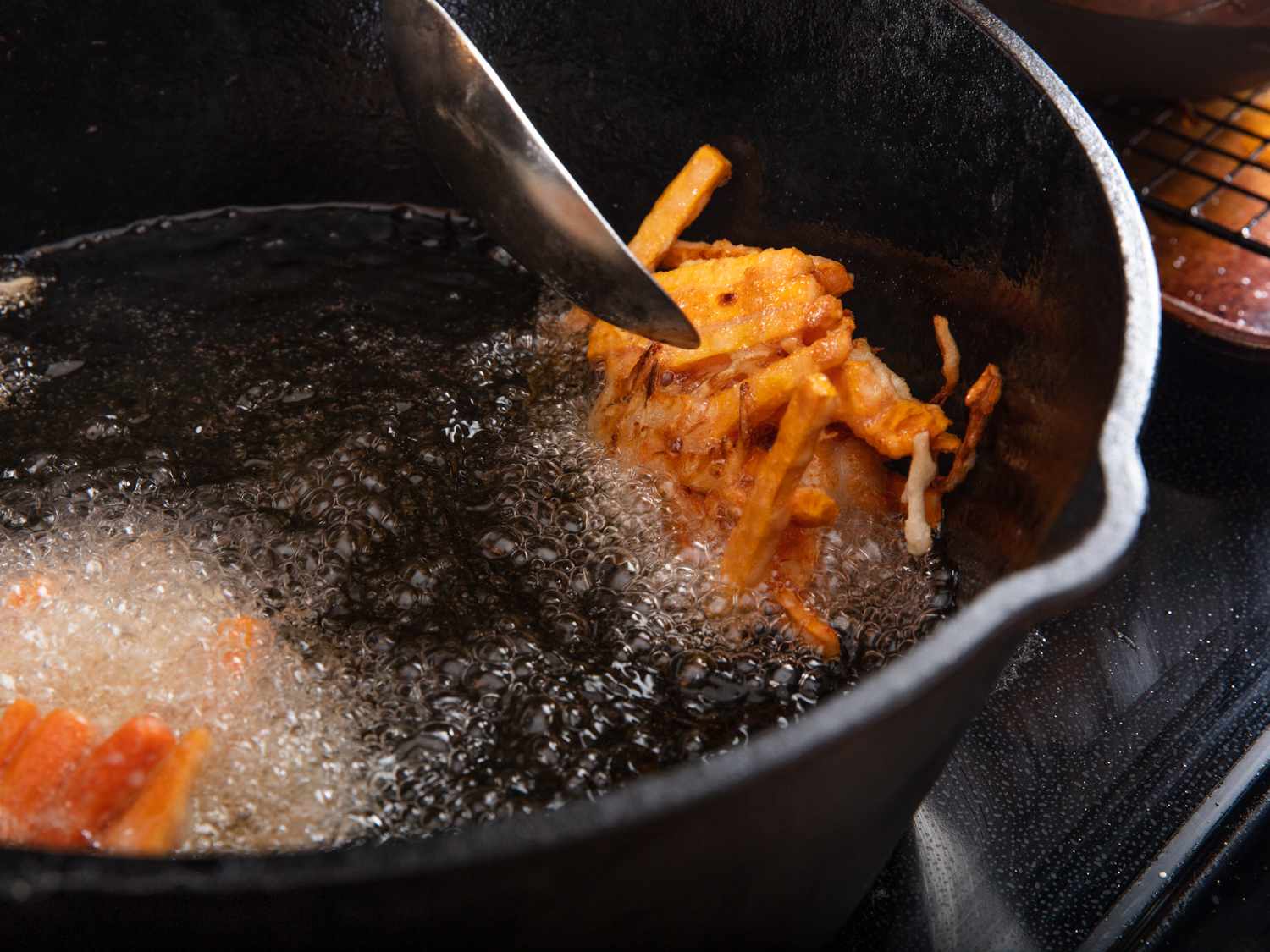 Closeup of frying ukoy in cast iron skillet