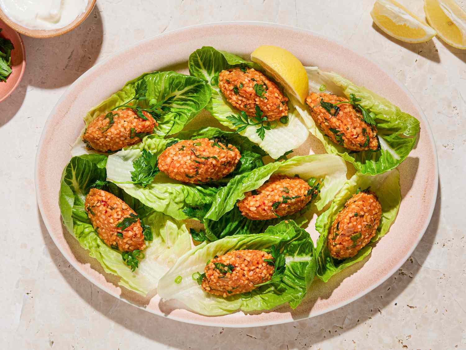 Turkish lentil koftes served on lettuce leaves with lemon wedges