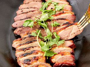 Sliced smoked duck breasts garnished with fresh herbs
