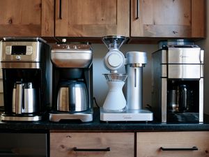 four coffee makers with built-in grinders lined up on a kitchen counter