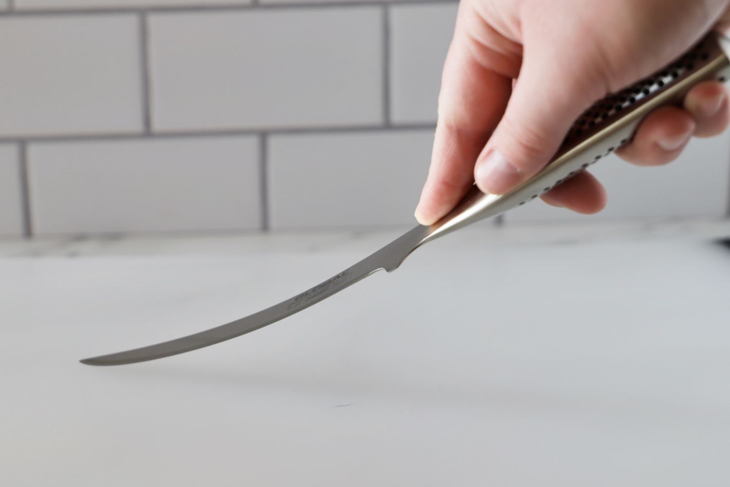 A hand holding the Global 6.25 inch Boning Knife Test