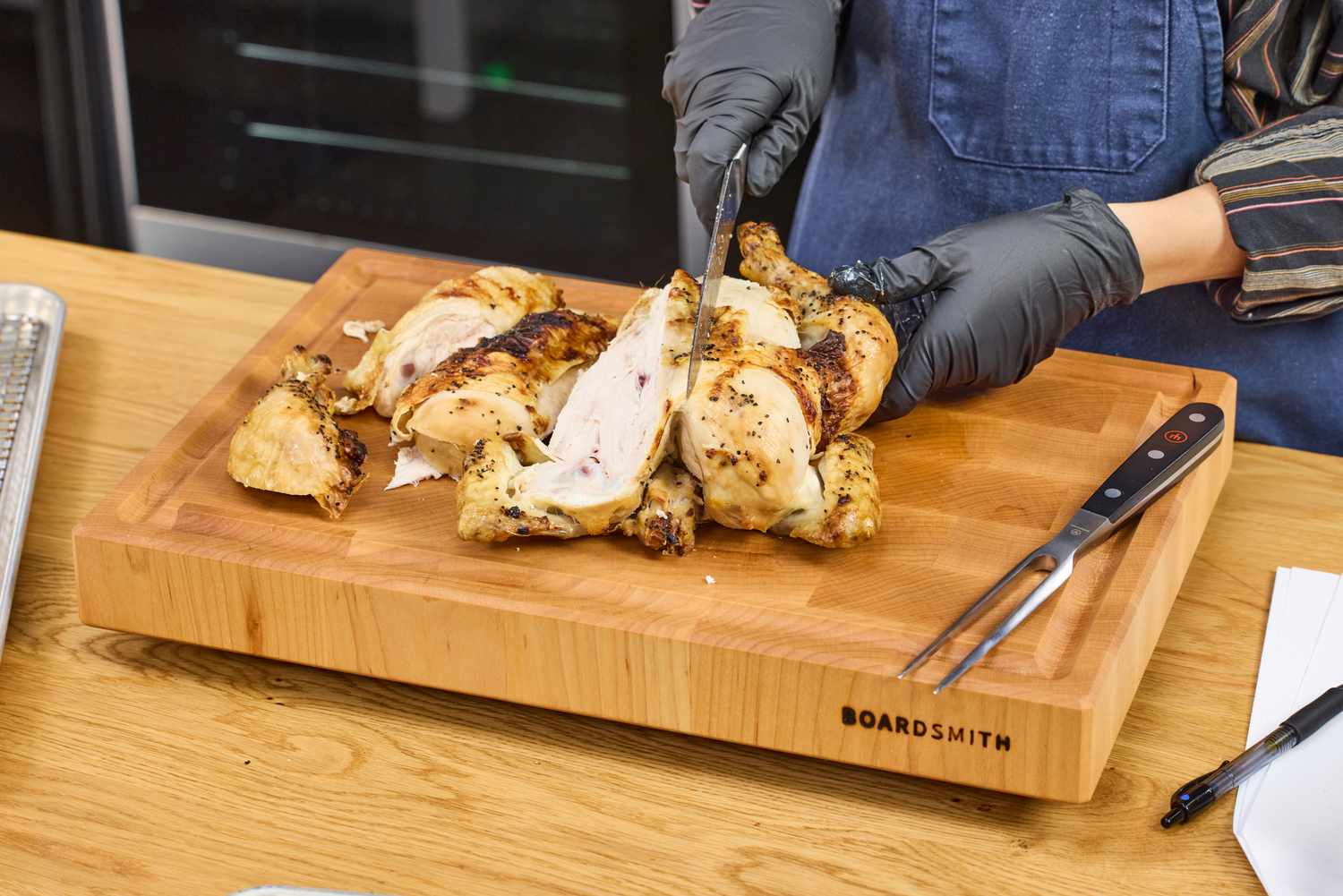 Person carving a roasted chicken on a Boardsmith Maple End-Grain Cutting Board