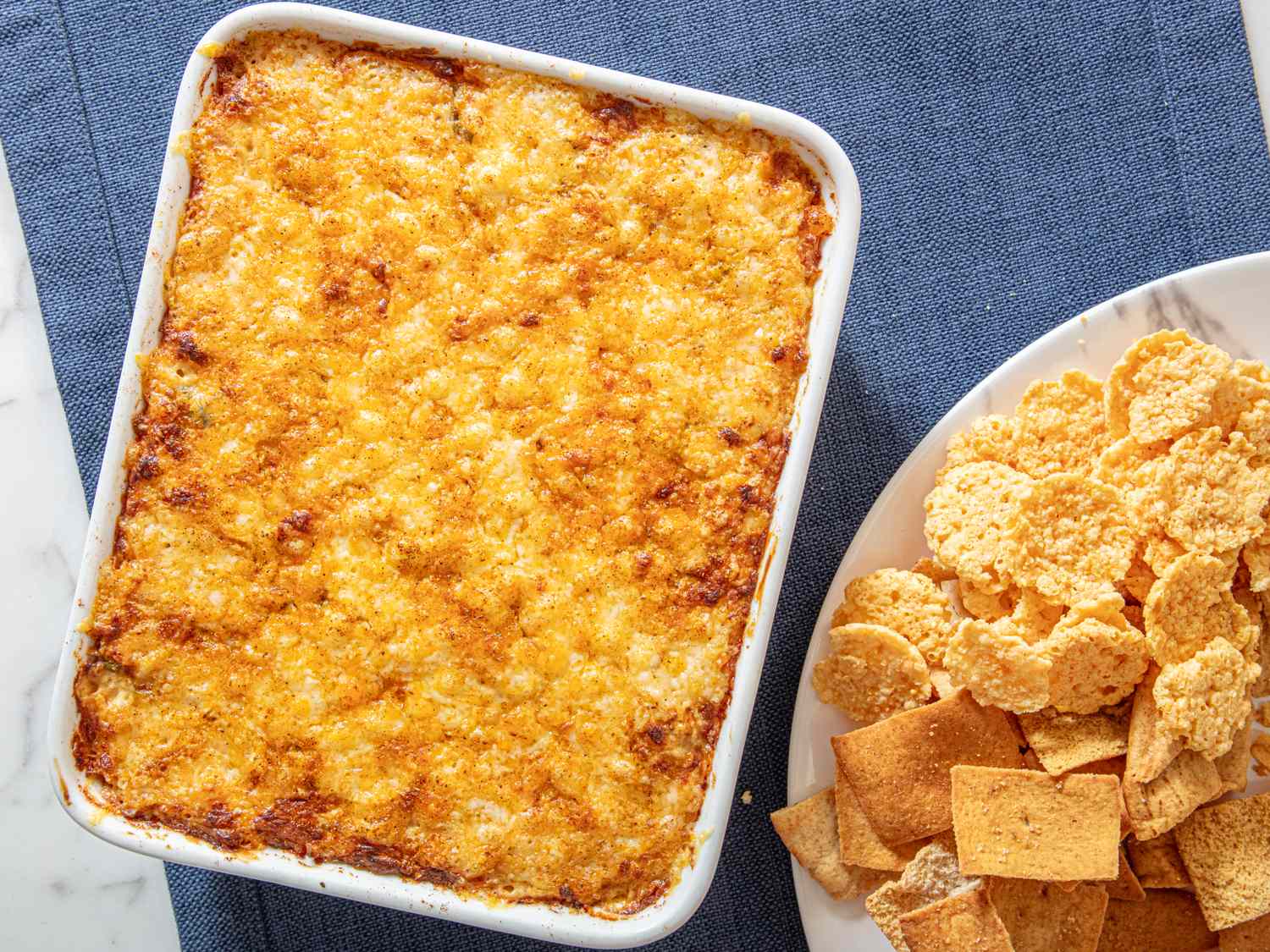 Baked crab dip in a dish served with various crackers on the side