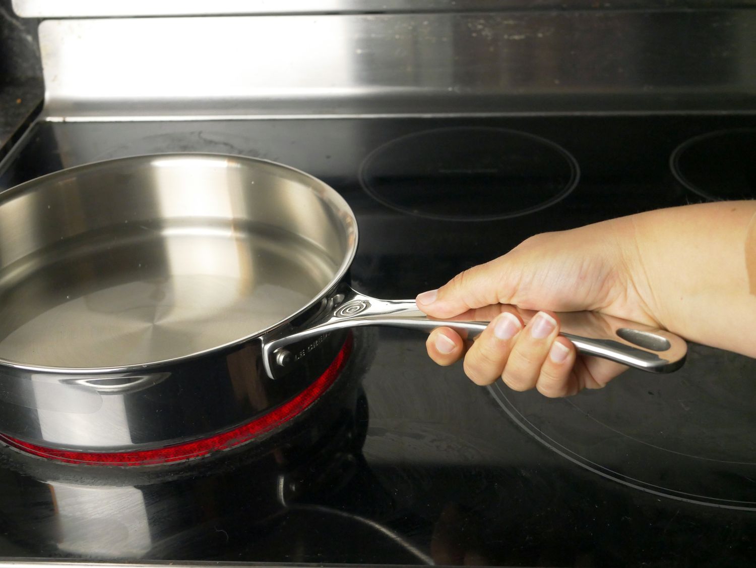 a person holding the handle on the le creuset skillet