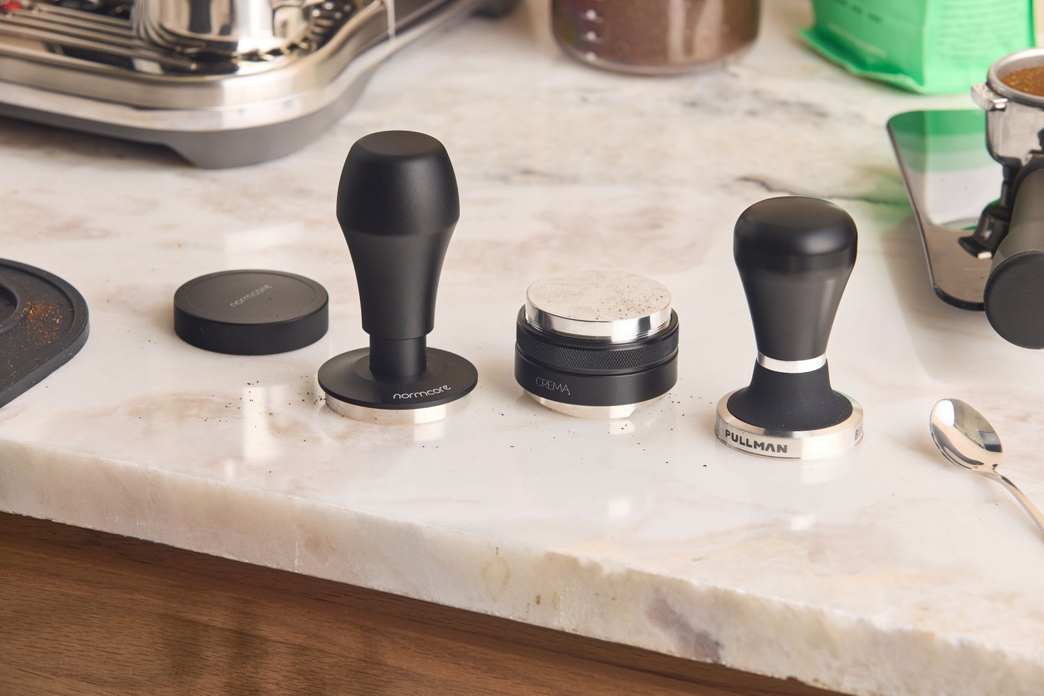 Three espresso tampers on a marble kitchen countertop.
