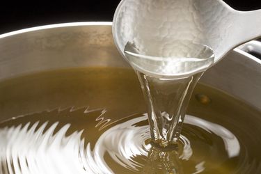 Closeup of a ladle pouring dashi back into a pot.