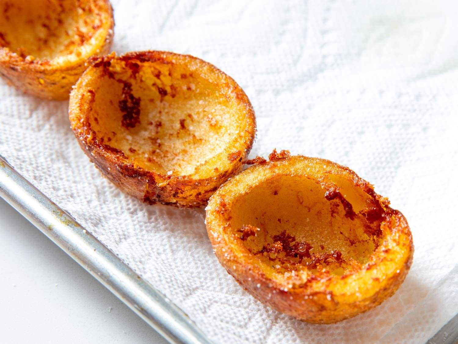 Fried potato skin cups drain on paper towels.