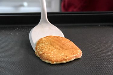 A person using the Material Soft-Edged Turner to flip food