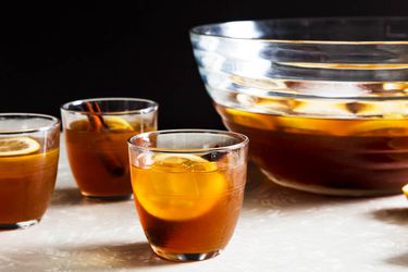 Make-ahead fig and cinnamon punch, served in glasses next to a punch bowl.