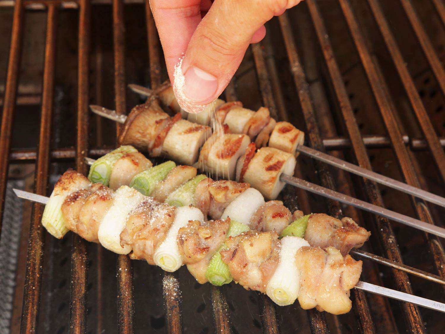 Sprinkling salt onto a yakitori skewer. 
