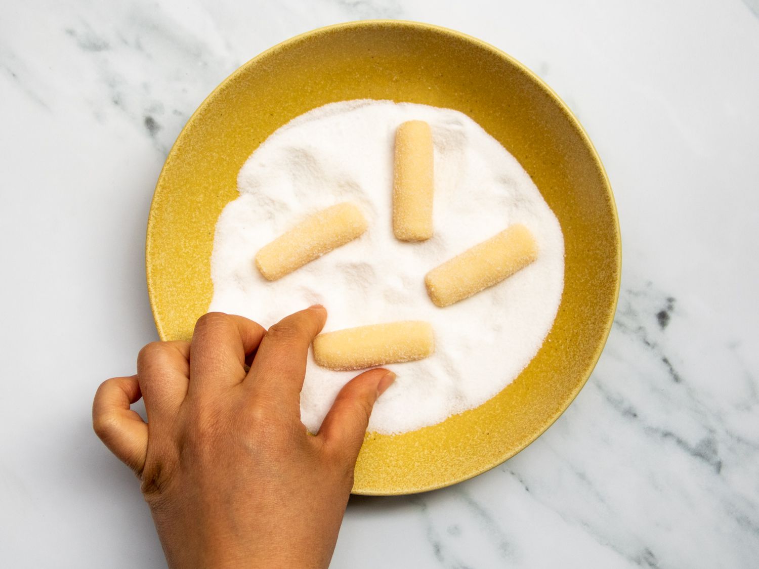 rolling pastillas de leche logs in sugar to coat