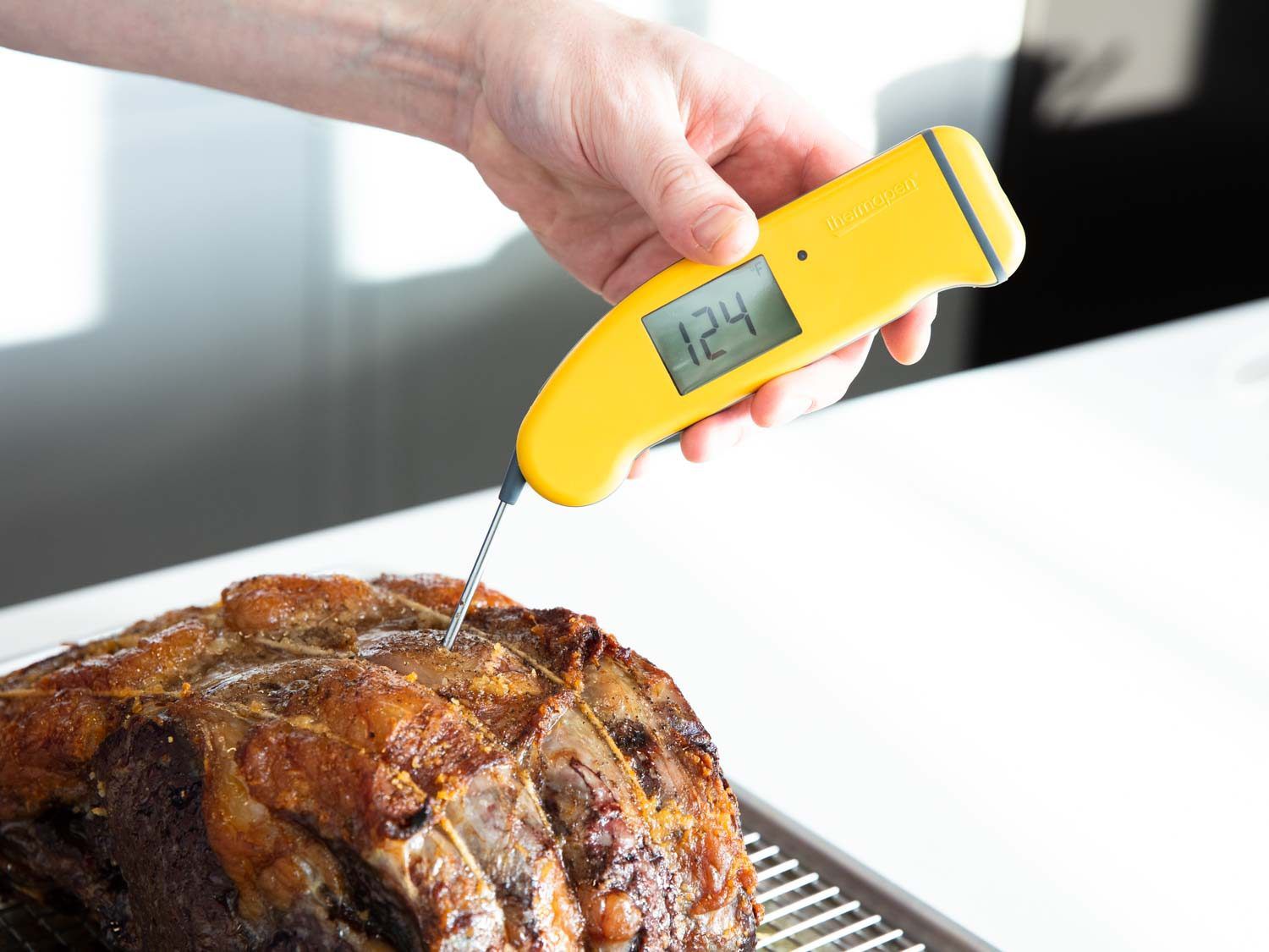 Checking the temperature of the prime rib with an instant-read thermometer. The display reads 124 degrees Fahrenheit.