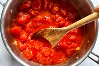 A pot of tomato sauce being stirred with a Sabatier All-Purpose Spoon